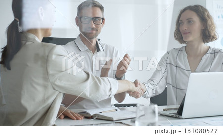 Businesswomen partners are shaking hands after successful negotiation, colleagues clapping, celebrating agreement in modern office headset. Handshake concept, view through the glass door Businesswomen partners are shaking hands after successful negotiation, colleagues clapping, celebrating agreement in modern office headset. Handshake concept, view through the glass door 131080527