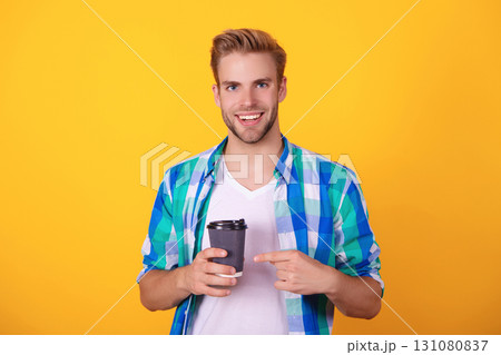 Millennial man having coffee cup isolated on yellow. Morning coffee time. Lifestyle concept. Drinking espresso. Man drinking tea. Warm morning. Coffee break at home. Point finger Millennial man having coffee cup isolated on yellow. Morning coffee time. Lifestyle concept. Drinking espresso. Man drinking tea. Warm morning. Coffee break at home. Point finger 131080837