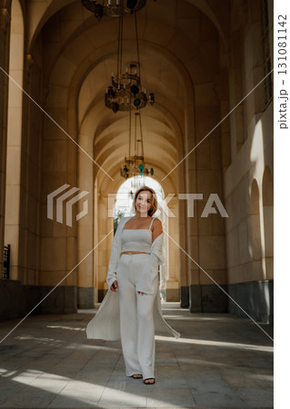 Woman White Outfit Architecture Corridor - A woman in a white outfit stands in a corridor with stone arches. Woman White Outfit Architecture Corridor - A woman in a white outfit stands in a corridor with stone arches. 131081142