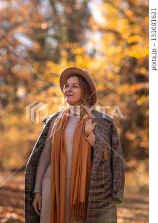 Woman Autumn Forest Portrait: Stylish woman in coat and hat enjoys fall foliage during autumnal outdoor photoshoot. Woman Autumn Forest Portrait: Stylish woman in coat and hat enjoys fall foliage during autumnal outdoor photoshoot. 131081621