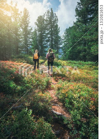 Two young women with backpacks hiking on a forest path Two young women with backpacks hiking on a forest path 131081653