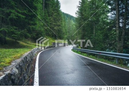 Wet mountain road curving through dense green forest Wet mountain road curving through dense green forest 131081654