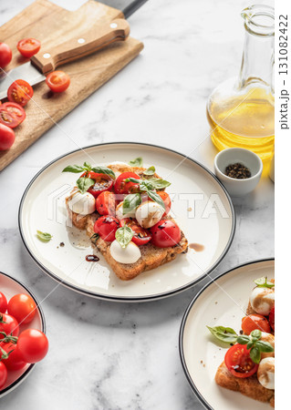 Caprese sandwich or toast with mozzarrella balls, cherry tomatoes, olive oil, pepper and fresh basil leaves. Healthy vegetarian breakfast, snack or lunch. White marble background 131082422