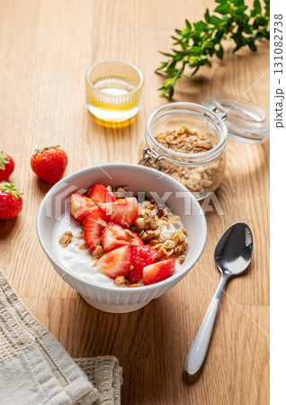 Granola or muesli with natural greek yogurt, strawberry and honey in a bowl on a wooden background Granola or muesli with natural greek yogurt, strawberry and honey in a bowl on a wooden background 131082738