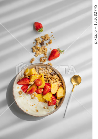 Granola or muesli with natural greek yogurt, strawberry and peach in a bowl on a white background Granola or muesli with natural greek yogurt, strawberry and peach in a bowl on a white background 131082745