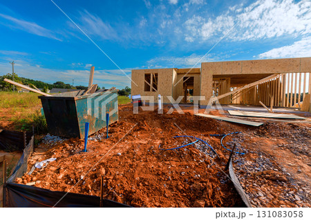 Construction site new house being built with materials scattered near waste dumpster 131083058