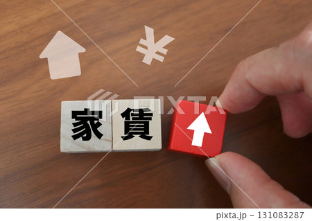 家賃値上げと生活負担増を象徴するブロックと矢印 131083287