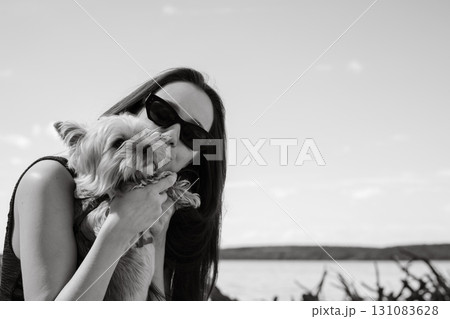 A young brunette woman kisses her adorable Yorkshire terrier dog in a moment of affection. A woman in sunglasses kisses her small doggy A young brunette woman kisses her adorable Yorkshire terrier dog in a moment of affection. A woman in sunglasses kisses her small doggy 131083628