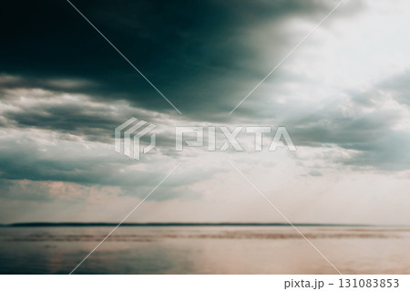 A moody sky with dark clouds over calm water, a tranquil scene of nature's beauty. Dramatic cloudy sky over calm water with a lone bird in flight, evoking a sense of peace and vastness. A moody sky with dark clouds over calm water, a tranquil scene of nature's beauty. Dramatic cloudy sky over calm water with a lone bird in flight, evoking a sense of peace and vastness. 131083853