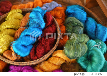 Tie of colorful and shiny beautiful silk yarn dyed placed in a pile of round bamboo baskets. Prepared for use as a raw material for weaving silk. 131083970