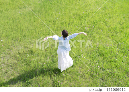 野原で深呼吸をする女性 俯瞰撮影 後ろ姿 野原で深呼吸をする女性 俯瞰撮影 後ろ姿 131086912