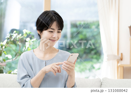 ソファーに座りスマートフォンを使う若い女性 131088042