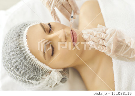Young woman receives filler injection in lips to make them plumper and more beautiful Young woman receives filler injection in lips to make them plumper and more beautiful 131088119