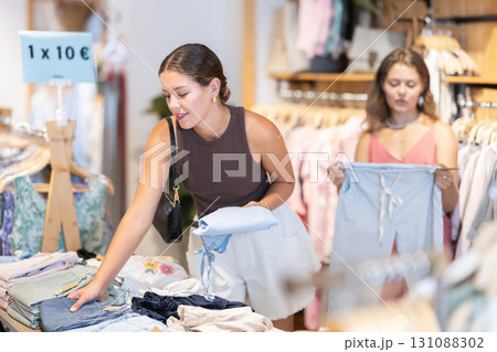 Two young women choosing a dress and other clothes in clothing store 131088302