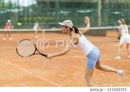 Female athlete plays tennis on open court Female athlete plays tennis on open court 131088355