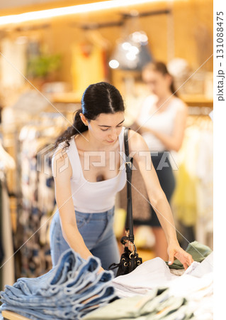 Girl customer chooses denim knee breeches or shorts in store 131088475