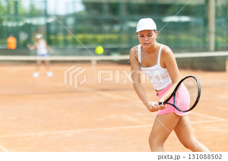 Concentrated sporty girl with tennis racquet and ball in her hands standing and ready to play match standing 131088502