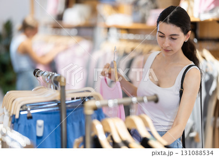 Girl customer chooses blouse in branded store Girl customer chooses blouse in branded store 131088534