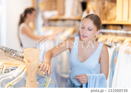 Young girl chooses something in branded clothing store Young girl chooses something in branded clothing store 131088536