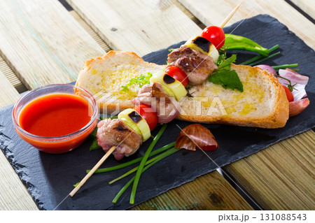 Baked shashlik of lamb with onion and tomatoes served with ketchup and bread Baked shashlik of lamb with onion and tomatoes served with ketchup and bread 131088543