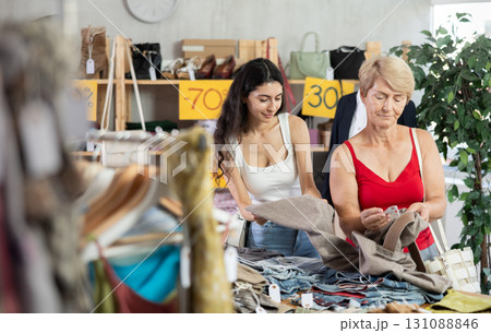 Woman customer with senior mother making choice and elect pants in store Woman customer with senior mother making choice and elect pants in store 131088846