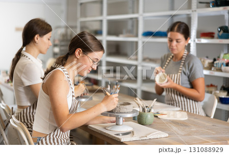 Woman teacher and students sculpt and paint ceramics Woman teacher and students sculpt and paint ceramics 131088929