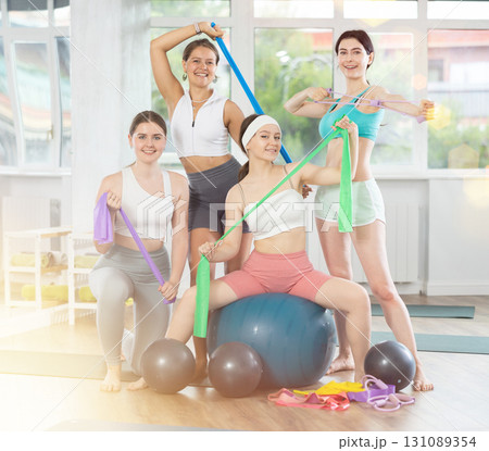Girl coach and young female visitors of fitness course smile happily after training Girl coach and young female visitors of fitness course smile happily after training 131089354