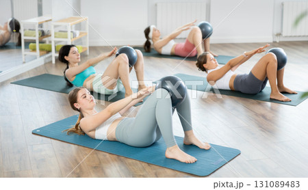 Young girls doing press with softball band between legs lying on the floor 131089483