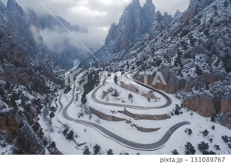 Winding Mountain Road Through Snowy Peaks and Misty Valleys, Aer 131089767