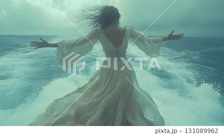 Woman in White Dress Embraces Ocean, Hair Blowing in the Wind 131089962
