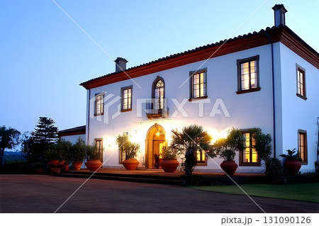 Elegant Estate House at Dusk with Warm Lighting and Lush Landsca 131090126