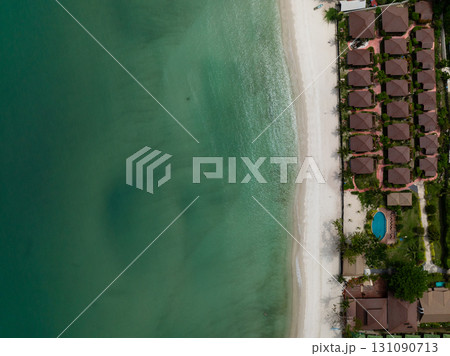 Tropical coastline beach villas with a pool and lush greenery along a pristine white sand beach and turquoise water. Ko Pha Ngan, Thailand. 131090713