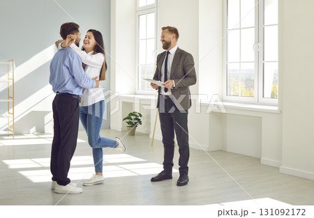 Woman holding home keys while hugging boyfriend in their new apartment after buying real estate. 131092172