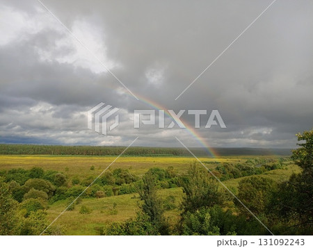 Rainbow in summer over the river, forest and fields, clouds with blue gaps in the sky, beauty Rainbow in summer over the river, forest and fields, clouds with blue gaps in the sky, beauty 131092243