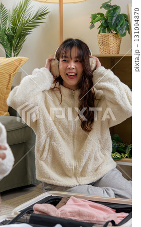 Winter day inspires warm friendship, women friends enjoy home comfort, cozy clothing earmuffs for winter journeys, happy cheerful moments at home preparing for adventure. 131094870