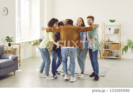 Group of happy friends greeting each other when they meet hugging indoors together. 131095080