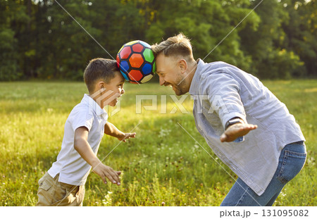 Happy father and son are having fun and playing with ball in green park in summer 131095082