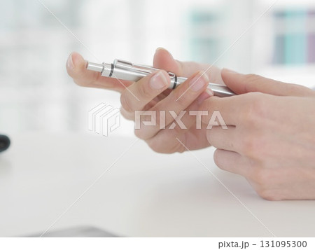 Person holding a pen and a small device Person holding a pen and a small device 131095300