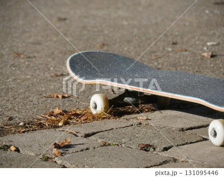 Skateboard is laying on the ground with its wheels up 131095446
