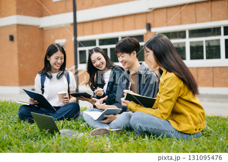 Young Asian college students and a female student group work at the campus park Young Asian college students and a female student group work at the campus park 131095476