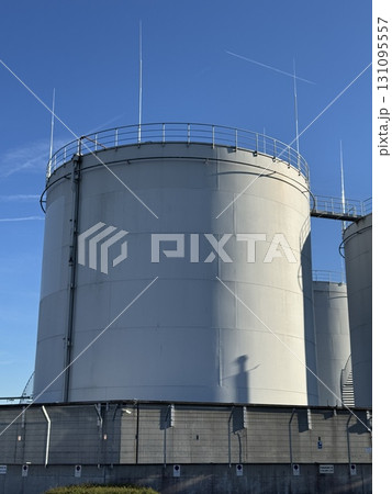 Large industrial storage tanks are situated under a clear blue sky showcasing modern infrastructure Large industrial storage tanks are situated under a clear blue sky showcasing modern infrastructure 131095557