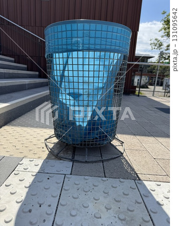 A blue wire trash bin along the pathway boosts both aesthetics and functionality A blue wire trash bin along the pathway boosts both aesthetics and functionality 131095642