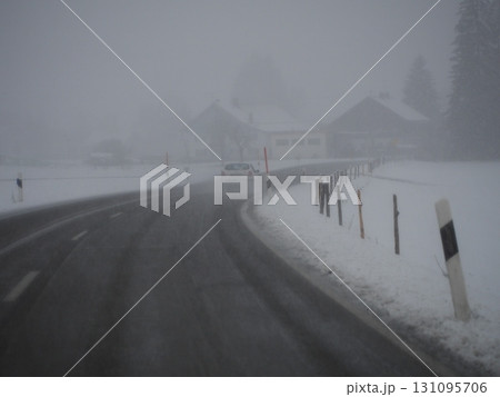 Snowy road with a car driving down it Snowy road with a car driving down it 131095706