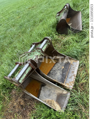 Rusty excavator buckets sitting abandoned on a patch of grass in a rural outdoor setting Rusty excavator buckets sitting abandoned on a patch of grass in a rural outdoor setting 131095853
