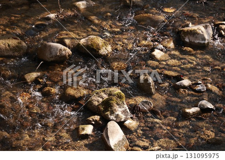 A stream of water is flowing over a rocky river bed 131095975