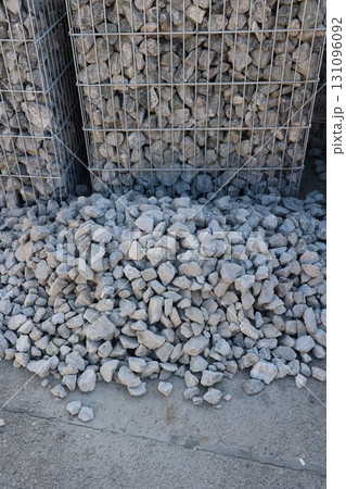 A pile of rocks is sitting on the ground next to a metal fence 131096092
