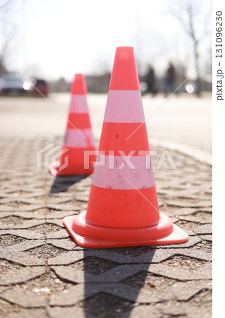 Two orange and white traffic cones are on the ground Two orange and white traffic cones are on the ground 131096230