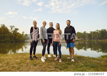 Happy young sport group of people jumping standing in a circle with hands up in nature. 131096337