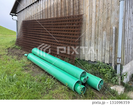 Green pipe is next to a wooden fence 131096359