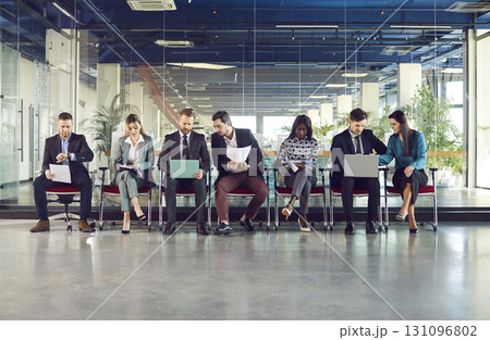 Group of diverse smart people in modern office lobby chair row sitting, working with laptops Group of diverse smart people in modern office lobby chair row sitting, working with laptops 131096802
